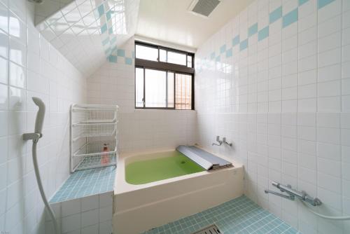 东京纳卡大雅旅馆的一间带绿色浴缸和窗户的浴室