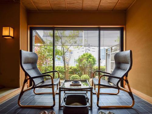 松山道后温泉大和屋别荘的窗户客房内的两把椅子和一张桌子