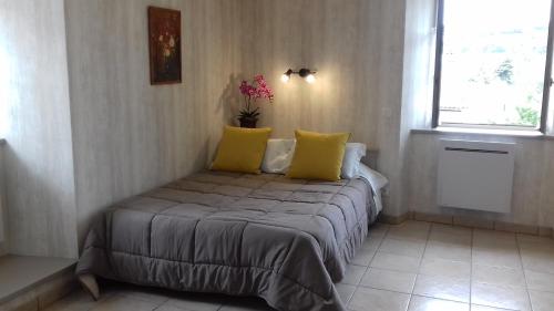 勒布伊Le Petit St Jacques的一间卧室配有一张带黄色枕头的床和一扇窗户