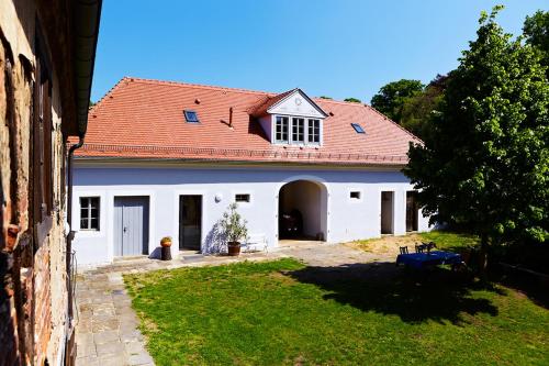 拉德博伊尔Weingut Haus Steinbach的白色的房子,有红色的屋顶和院子
