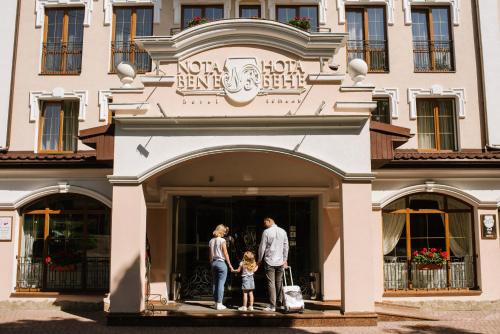 利沃夫Nota Bene Hotel & Restaurant的站在建筑物前的男女和儿童