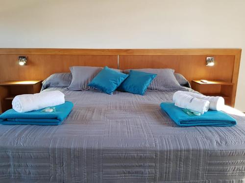 本塔纳山村Posada de la comarca的一张大床,上面有两个蓝色的枕头