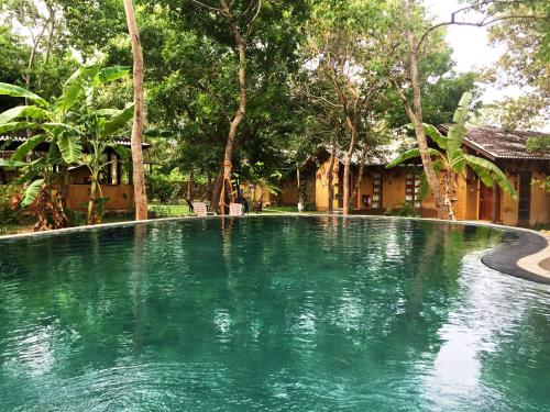 锡吉里亚Sat Nam Village Eco-Hotel的一座树木繁茂的房屋前的游泳池