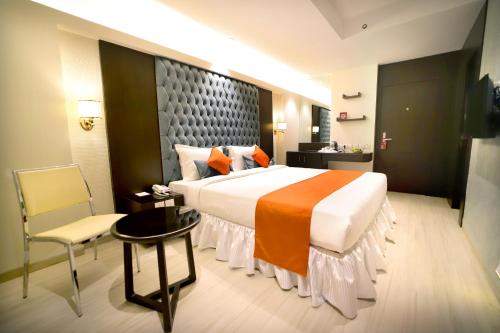 加尔各答南部广场酒店的酒店客房带一张大床和一把椅子