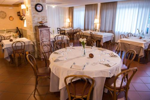 佩斯卡塞罗利艾瑞斯酒店的用餐室配有桌椅和白色的桌布