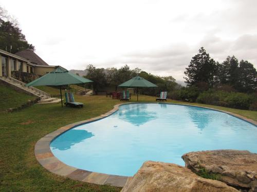 姆巴巴内Emafini Country Lodge的一个带遮阳伞的庭院里的大型蓝色游泳池