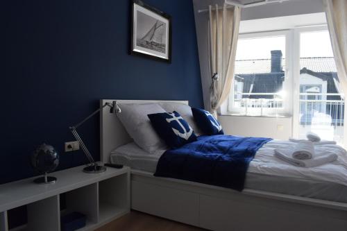 波别罗沃Apartament Silence Baltic Róża Wiatrów的一间卧室设有蓝色的墙壁和一张带窗户的床