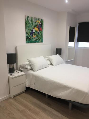 瓦伦西亚Garden Turia Downtown的卧室配有白色的床和墙上的绘画作品
