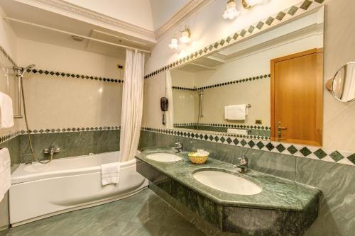 罗马康缇里亚酒店的浴室设有2个水槽、浴缸和镜子
