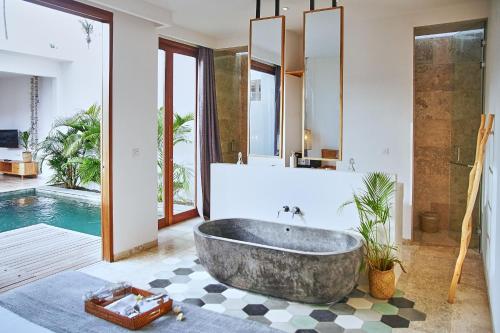 龙目岛库塔Kumbara Villas的一间带大浴缸和游泳池的浴室