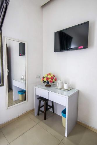 新山Rose Cottage Hotel Taman Impian Senai的客房设有书桌和墙上的电视。
