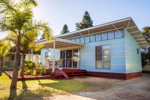 Tomakin巴林斯海滩假日公园的前面有棕榈树的蓝色房子