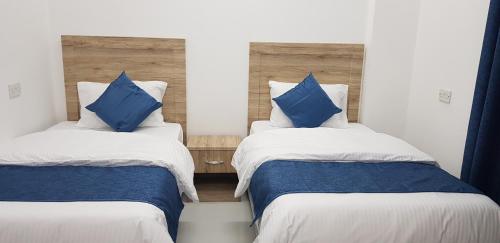 杜科姆Duqm Suites的配有蓝色枕头的客房内的两张床