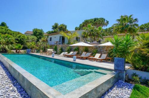 圣特罗佩villa Sant-Anna的房屋旁的游泳池配有椅子和遮阳伞