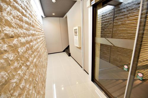 泉佐野KURA HOTEL IZUMISANO的走廊上设有玻璃门和砖墙
