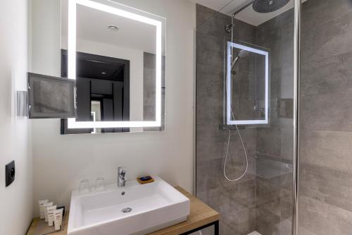 安特卫普Radisson Hotel Antwerp Berchem的浴室配有盥洗盆和带镜子的淋浴