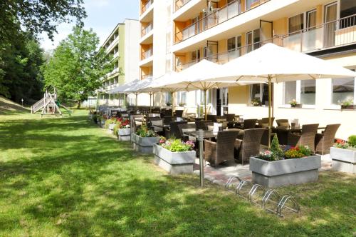 瓦赫河畔比斯特里察Hotel Garni的酒店庭院设有桌椅和遮阳伞。