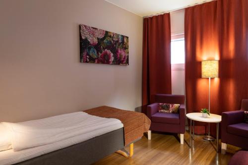 于默奥Hotell Vilja的酒店客房,配有一张床和两把椅子