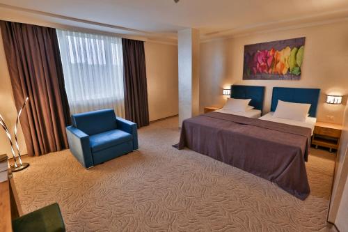 特尔戈维什特Terra Europe Brontes Hotel的酒店客房,配有一张床和一张蓝色椅子