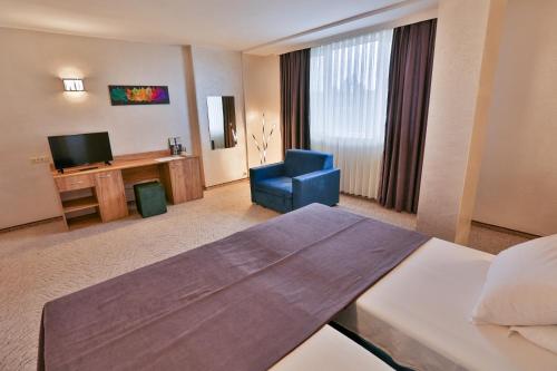 特尔戈维什特Terra Europe Brontes Hotel的酒店客房配有一张床、一把椅子和一台电视。