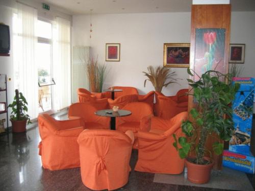 里米尼海滩酒店的客厅配有橙色椅子和桌子