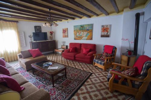 Urrea de GaenCasa Rural La Casona的客厅配有红色的沙发和椅子