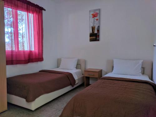 乌尔齐尼Beni Bungalows的一间卧室设有两张床,窗户配有粉红色的窗帘