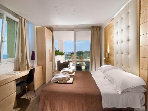 里乔内Hotel Sarti的一间卧室配有一张床、一张书桌和一个窗户。
