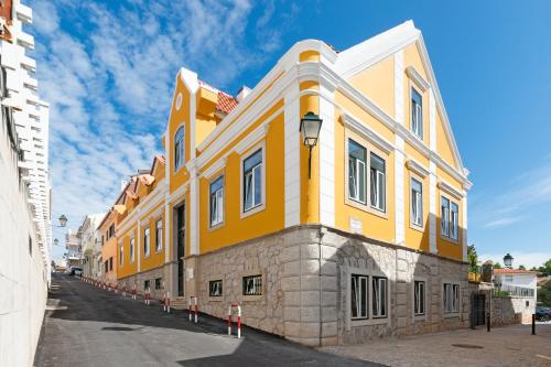 卡斯卡伊斯Bela Vista Palace Apartments的街道边的黄色建筑