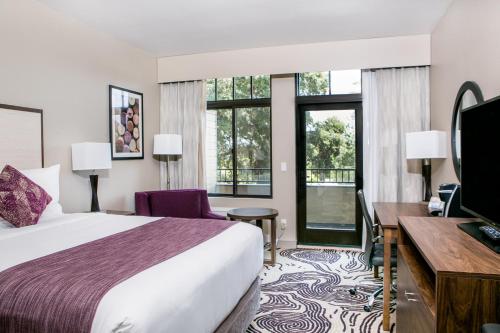佩索罗伯斯Hotel Siri Downtown - Paso Robles的酒店客房设有一张床、一张书桌和窗户。