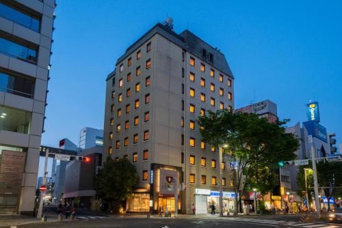 名古屋Hotel S-plus Nagoya Sakae的夜幕降临的城市街道上一座高楼