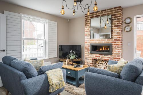坎伯利Owlers Cottage的客厅配有2把蓝色椅子和壁炉