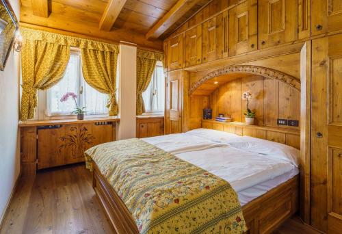 科尔蒂纳丹佩佐拉奎拉酒店的一间卧室配有一张带木墙的大床
