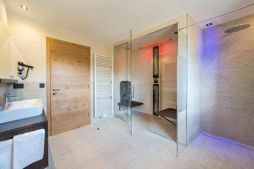 蒂鲁罗Hotel Zum Tiroler Adler的一间带玻璃淋浴和水槽的浴室