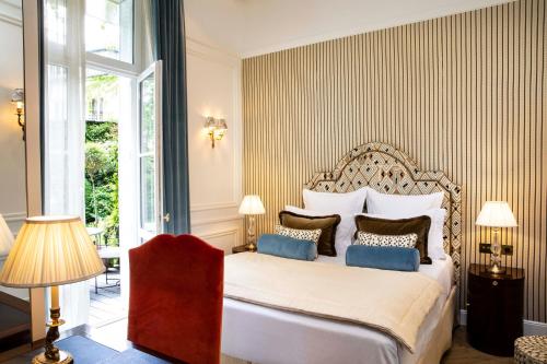 巴黎克里斯蒂娜驿站酒店的卧室配有带蓝色枕头的大型白色床