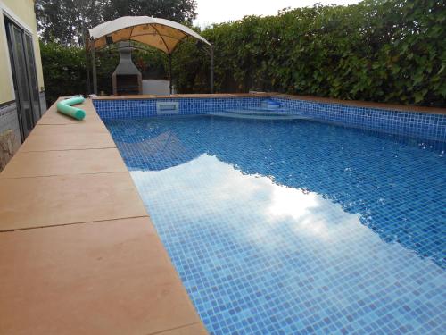 埃尔韦尔赫尔Casa La Madriguera的蓝色瓷砖游泳池,带雨伞