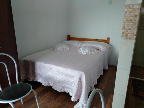纳韦甘蒂斯Hospedagem Navegantes的一间卧室配有一张带粉红色床单和椅子的床