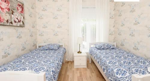 派尔努Roosi Apartment的卧室内的两张床,配有蓝色和白色的壁纸