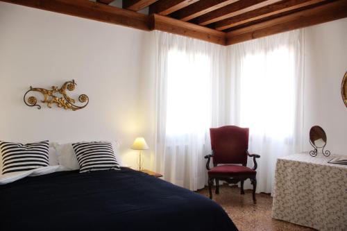 威尼斯圣卢卡公寓酒店的一间卧室配有一张床、一把椅子和窗户。