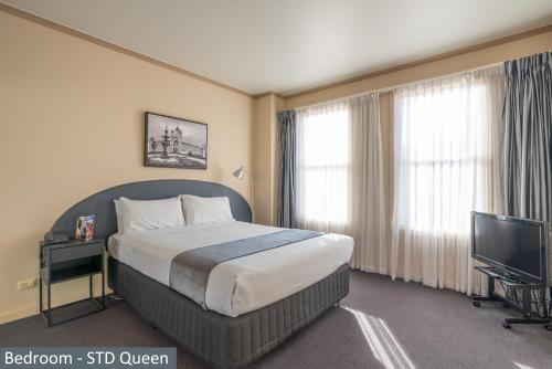 墨尔本Clocktower Apartment Hotel的配有一张床和一台平面电视的酒店客房