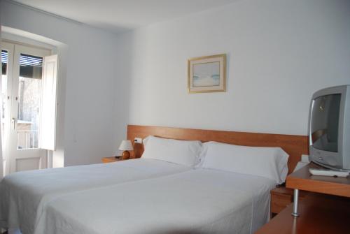 赫罗纳维拉多马特旅馆的卧室配有白色的床和电视