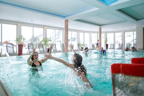 帕特加森Heidi-Hotel Falkertsee - Kinderhotel的两人在游泳池玩耍