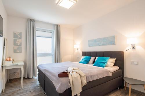 加兹尤瑟多姆Appartement "Dünentraum" - Oase am Haff的一间卧室配有一张带蓝色枕头的床和一扇窗户。