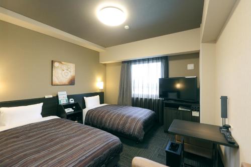 静冈Hotel Route-Inn Shimizu Inter的酒店客房设有两张床和一台平面电视。