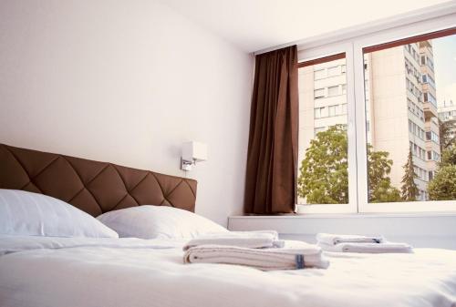 巴尼亚卢卡Hotel Slavija Banja Luka的一间卧室配有一张带白色床单的床和一扇窗户。