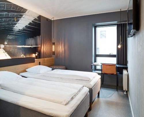 奥尔堡Zleep Hotel Aalborg的酒店客房设有三张床和一张书桌