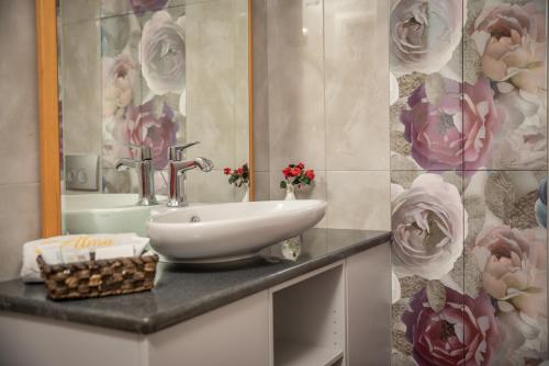 帕特雷Alma Hotel的浴室设有水槽、镜子和鲜花