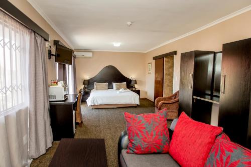 开普敦Oria Guest House的酒店客房配有一张床铺和一张带红色枕头的沙发。