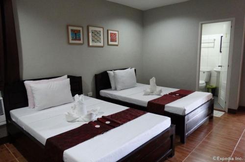 塔比拉兰海港花园旅游宾馆的一间卧室配有两张带白色床单的床