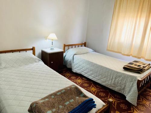 Curuzú CuatiáContinental Hotel的一间卧室设有两张床、一盏灯和一扇窗户。